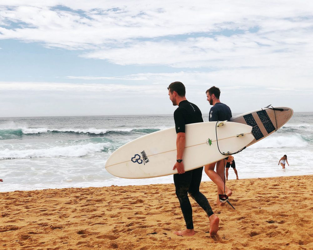 two-men-carrying-surfboards-near-seashore